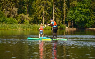 Lady giving child a high five whilst both on paddleboards