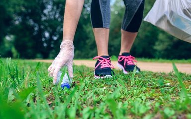 Person picking up litter from the grass