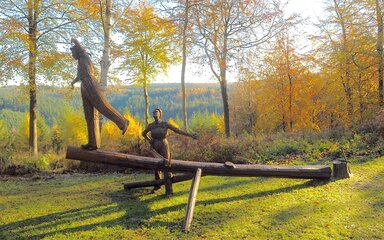 A rusted metal sculpture of two female foresters working on a tree.