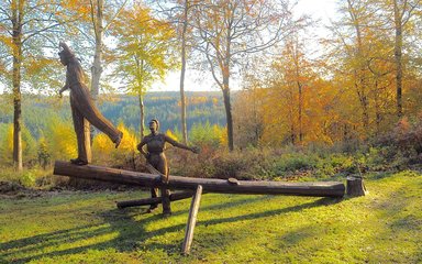 A rusted metal sculpture of two female foresters working on a tree.