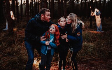 A family walking through an illuminated trail for Halloween in a forest