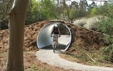 man on mountain bike riding through pipe tunnel 