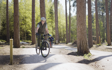 Boy standing up on his bike to go over some bumps on a cycle trail
