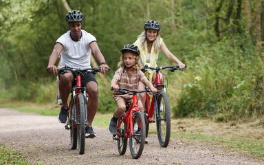 Two parents and a young child cycling in Salcey Forest