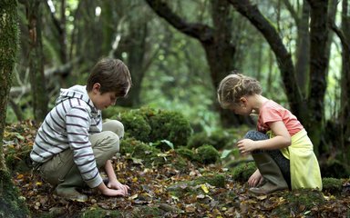 Children looking on forest floor scavenger hunt 