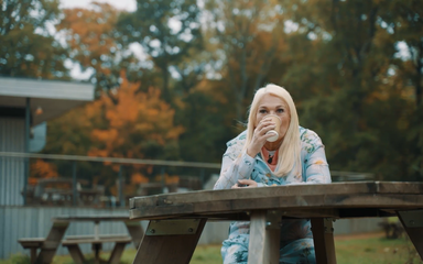 Vanessa Feltz drinking a coffee on a picnic bench.