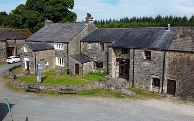 A large farmhouse-style building with trees behind
