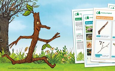 A digital illustration of Stick Man alongside a pile of example paper worksheets.