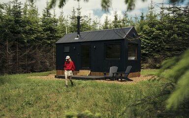 A woman walks out of a Unyoked cabin in Dalby Forest