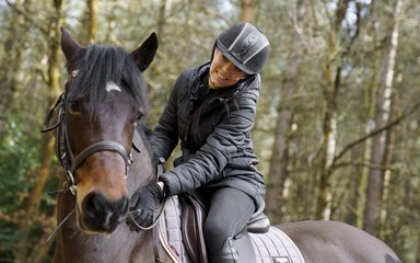 Woman on horse with woodland in the background