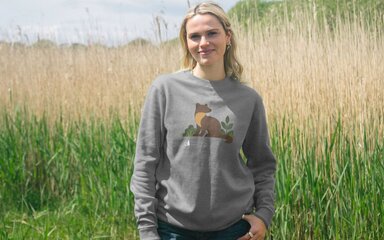 A white woman with blonde hair wearing a grey sweatshirt with a pine marten on.