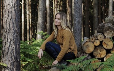 Jessica Cresswell sits next to log pile