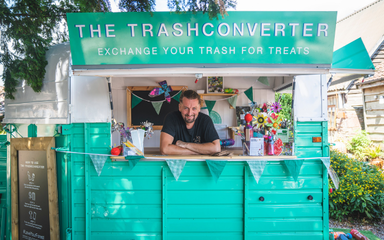 The trashconverter - a bright turquoise van with a friendly man in the hatch waiting to take your trash 