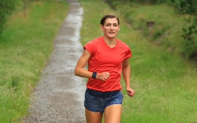 Verity Ockenden in a red jersey running along a woodland path