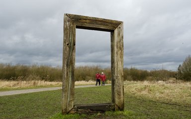 A couple walking by the side of a art installation at Viridor Woods