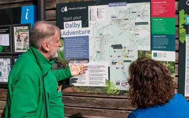 A volunteer showing a visitor a map of walking trails