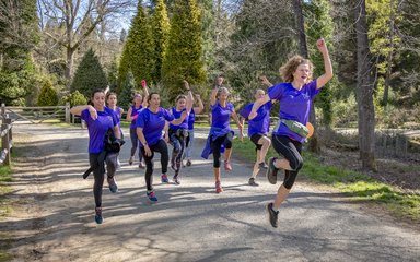 Group of runners in forest jumping in the air