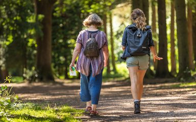 Two women walking towards trees in the forest