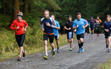 Adults running along forest path 