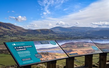 A viewpoint panel in the foreground with a lake and mountain behind