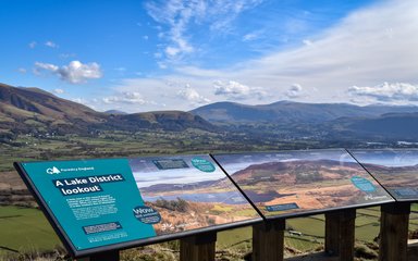 A viewpoint panel in the foreground with a lake and mountain behind