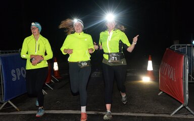Three runners wearing high viz and head torches