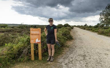 Recreation ranger Amy Howell standing next to a sign about nesting birds in the New Forest