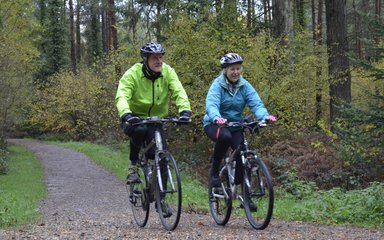 A couple cycling on a forest trail at Alice Holt