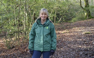 Jane, a volunteer ranger stand in a autumnal woodland