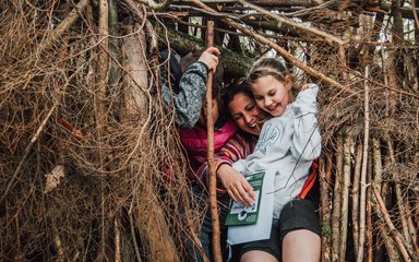 Family playing in a forest den