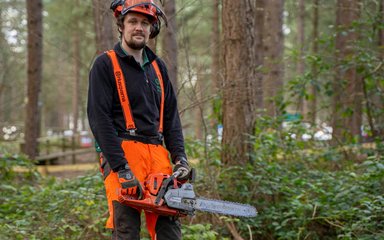 Staff wearing PPE and holding a chainsaw