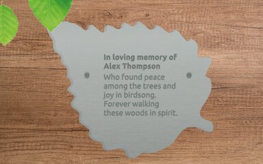 Digital illustration of a silver-coloured memorial plaque in the shape of a leaf.