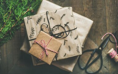 A stack of three gift wrapped in brown paper and tied with string.