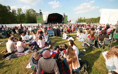 Crowd in the sun in front of a music stage in the woods
