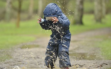 Young kid splashing in a puddle in wellies