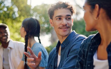 A group of young adults sit in a line chatting.
