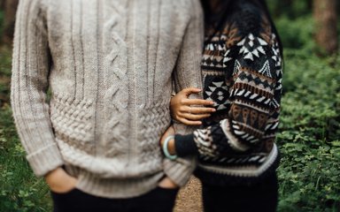 Couple in warm jumpers linking arms