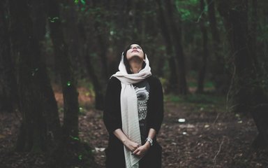 Woman looking up into forest canopy