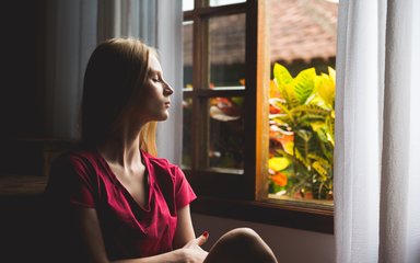 Woman with closed eyes facing out of a window