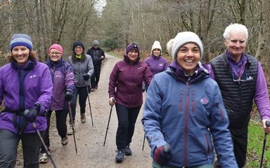 Smiling people walking through woodland in winter, with canes