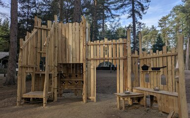 A wooden play fortress in a forest setting