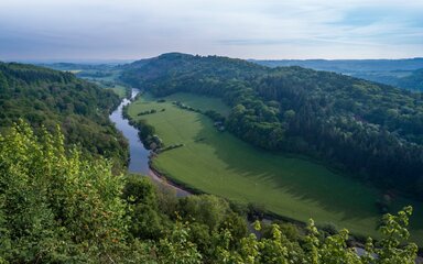 Looking down to a river winding through lush green landscape.