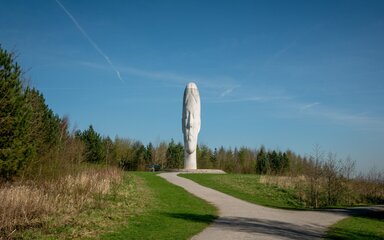 The Dream sculpture, a towering white head at Sutton Manor Country Park, viewed from a path through grassland.