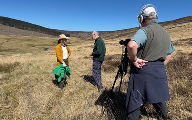 A woman being interviewed by two men outdoors.