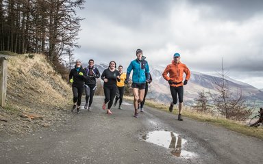 A group of seven runners on a hillside path