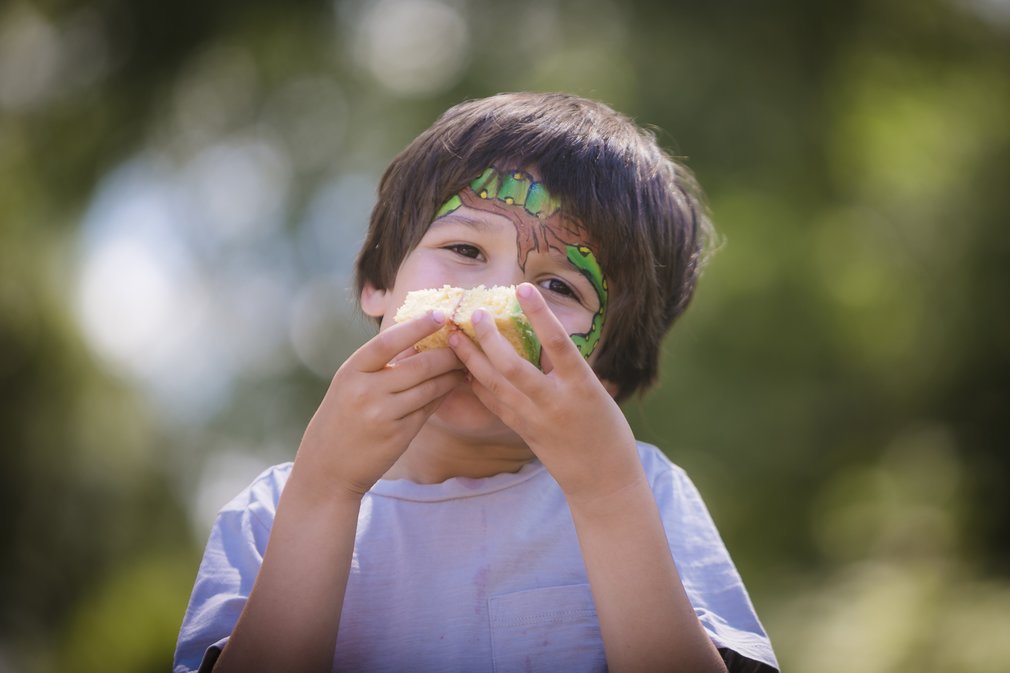 Boy with Gruffalo face paint eating a piece of cake