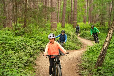 Family cycling through a forest path
