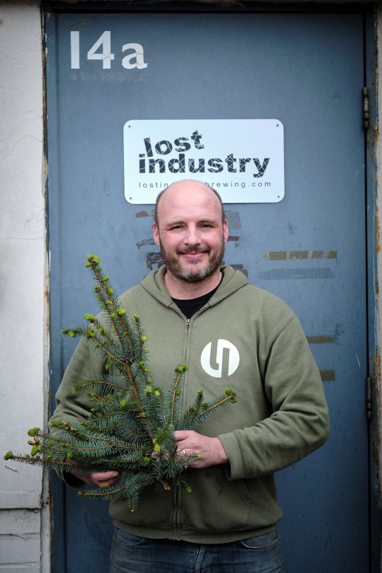 Man stood holding small tree smiling