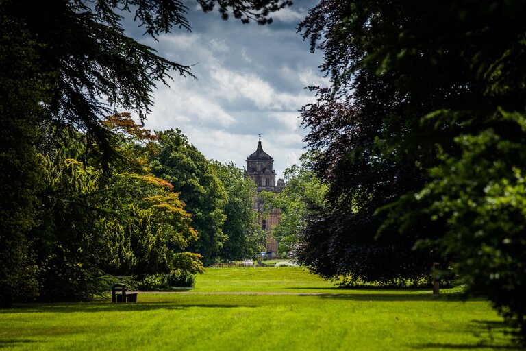 Holford Ride at Westonbirt Arboretum - a grassy ride with a tall building in the back ground covered by trees.