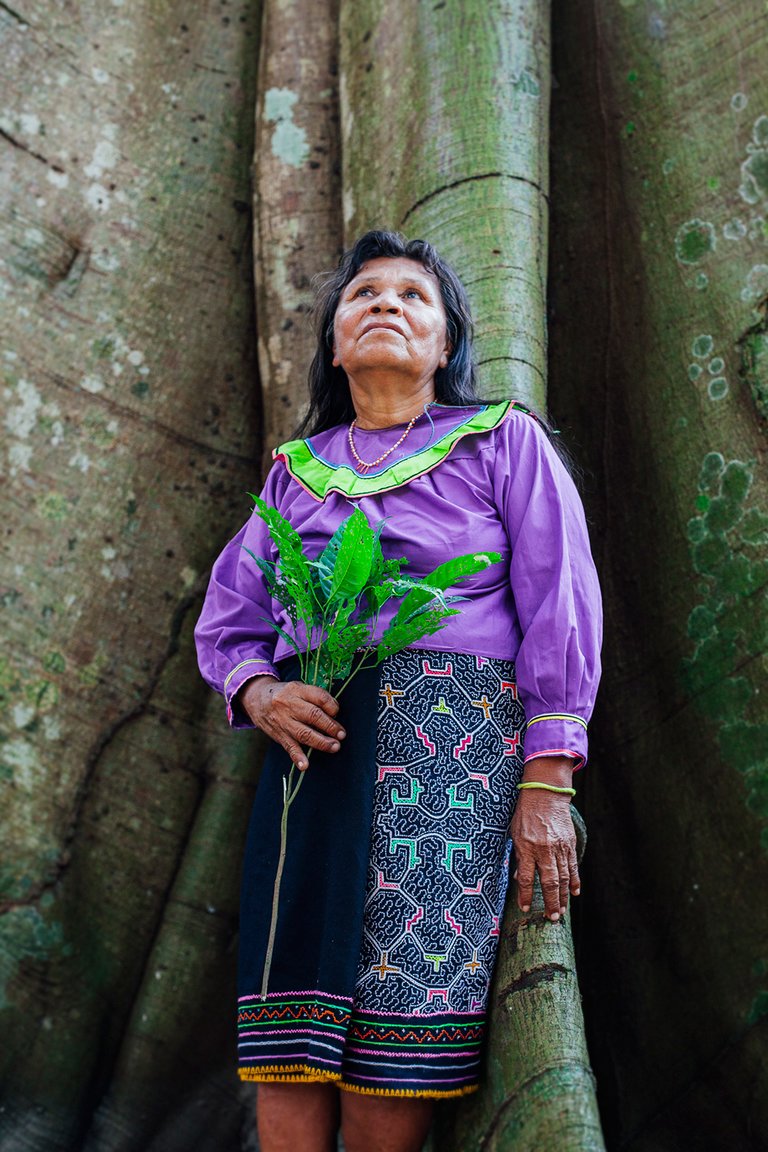 Woman standing below tree with leaves in her hand